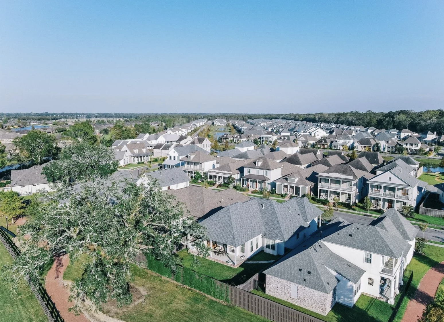 Aerial view of The Preserve at Harveston — white Acadian homes with lake and mature oaks
