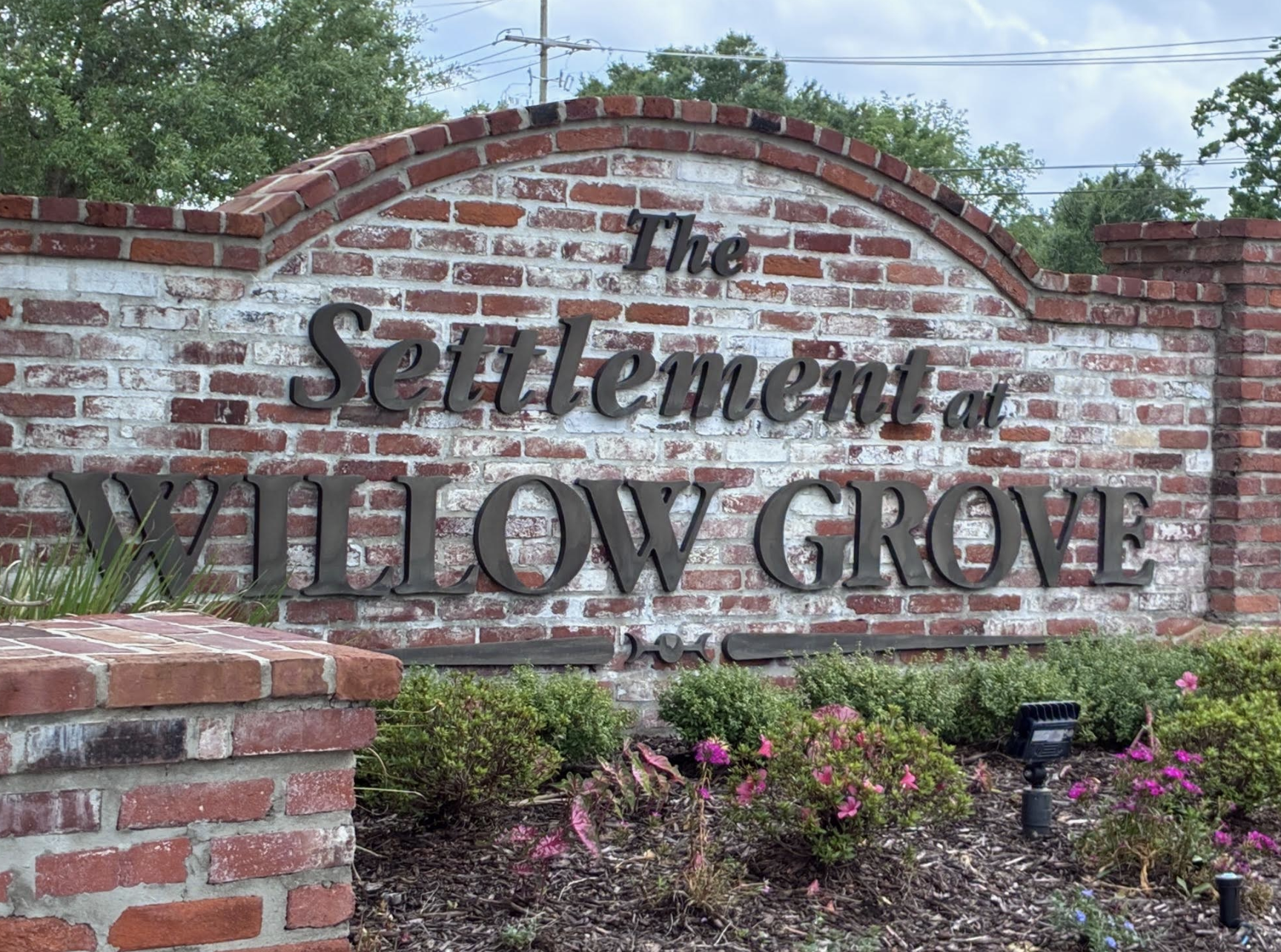 The Settlement at Willow Grove entrance sign — whitewashed brick with script lettering
