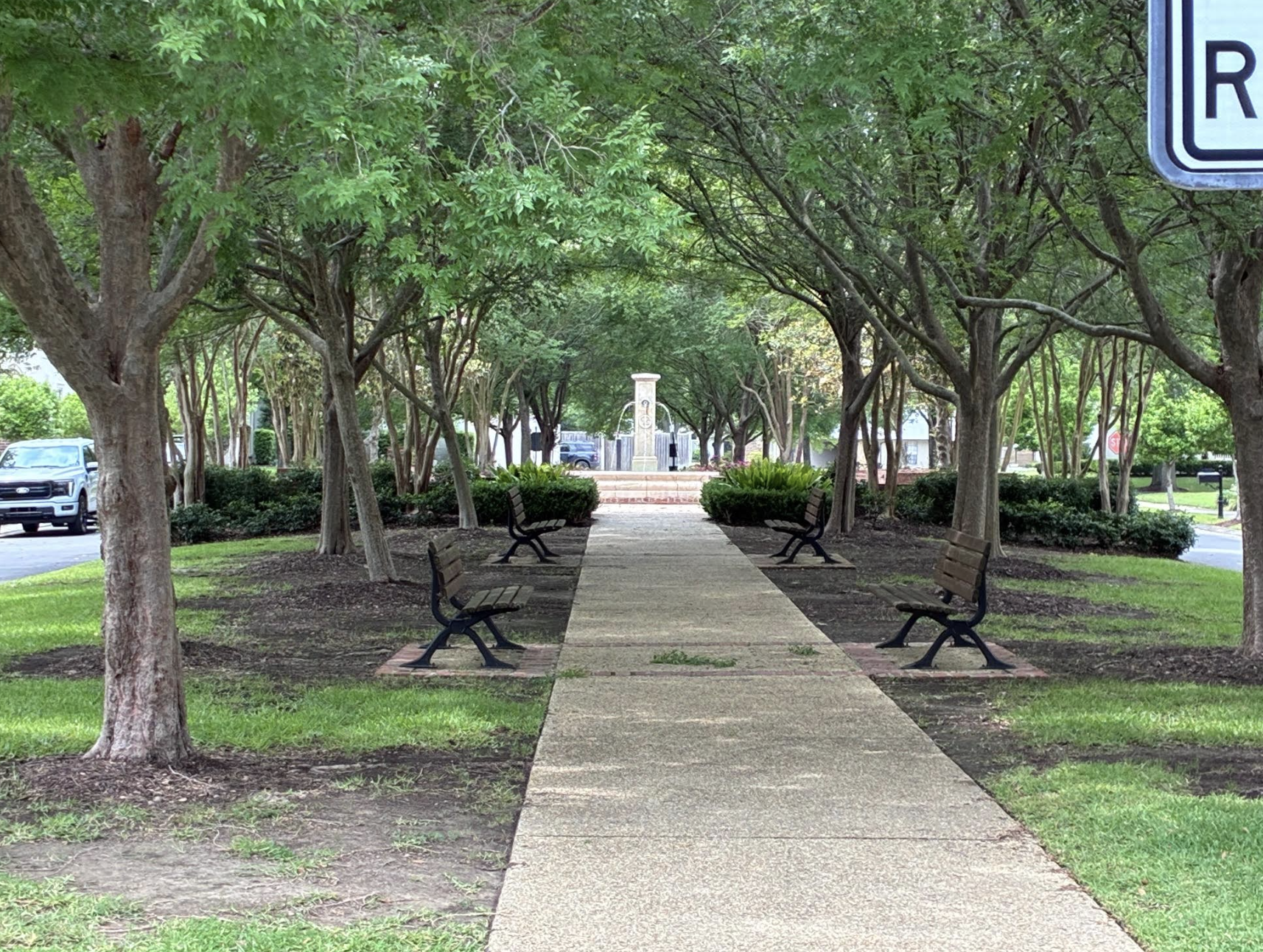 Tree-lined walkway with park benches leading to the fountain at Willow Grove